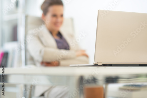 Closeup on laptop and business woman in background