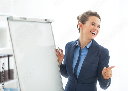 Smiling business woman near flipchart pointing photo