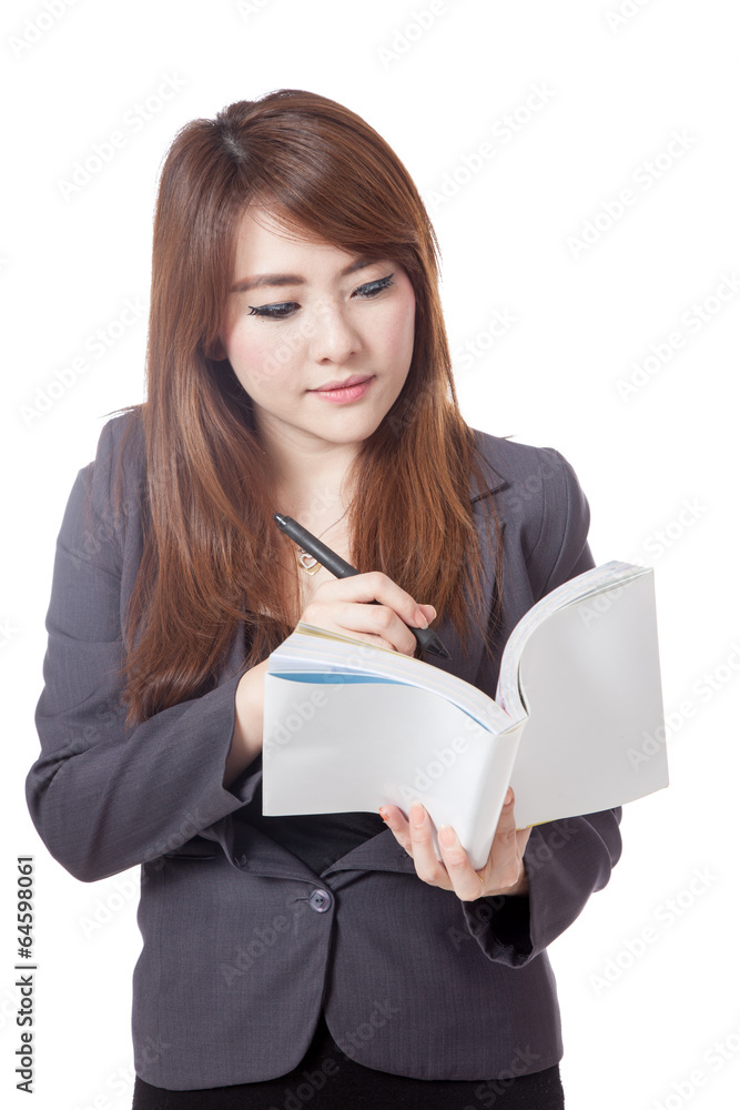 Asian businesswoman is thinking and writing note in a book Asian businesswoman is thinking and writing note in a book