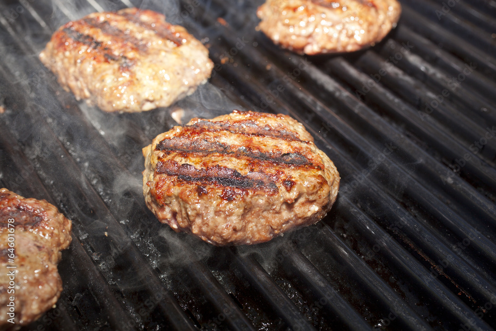 Hamburger patties cooking on a grill.