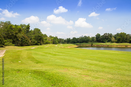 Golf course green grass and lake with cloudscape in background