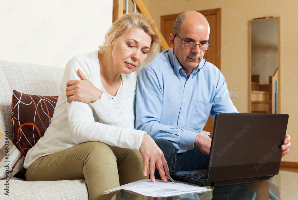 Family reading finance documents together and using laptop