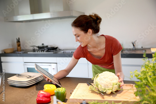 Woman in kitchen looking at recipe on tablet