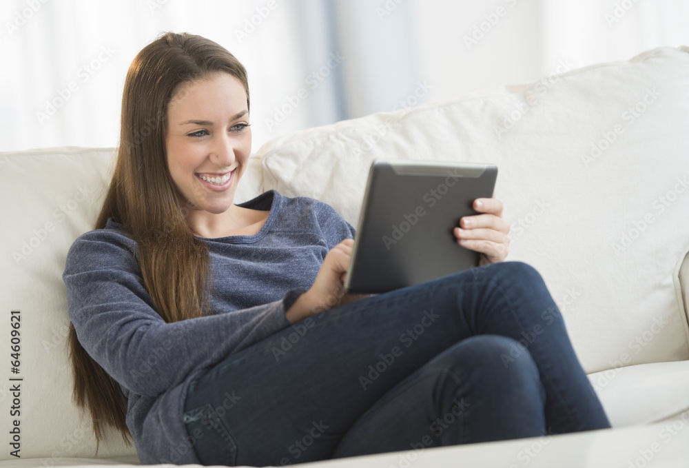 Woman Using Digital Tablet On Sofa Woman Using Digital Tablet On Sofa