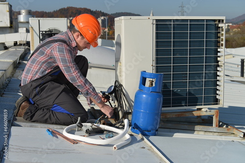 Air Conditioning Repair, young repairman on the roof fixing AC