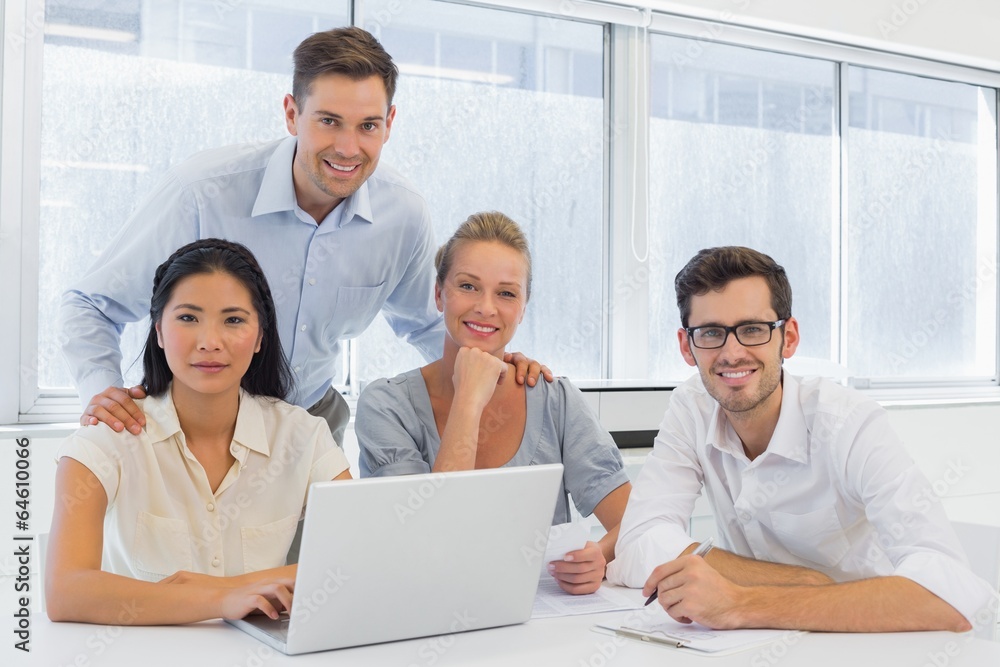Casual business team working together at desk using laptop
