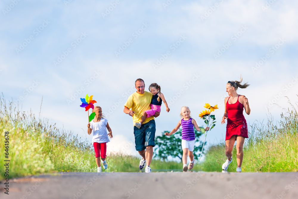 Family with three kids running down a hill in summer Family with three kids running down a hill in summer
