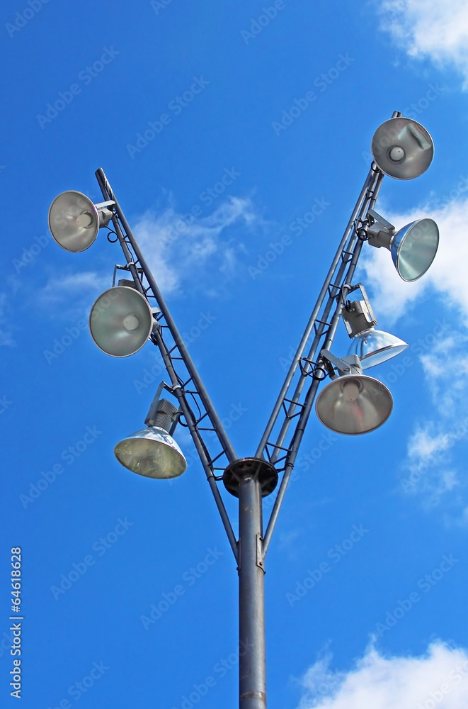 Modern pole with spotlights and blue sky with clouds behind Modern pole with spotlights and blue sky with clouds behind