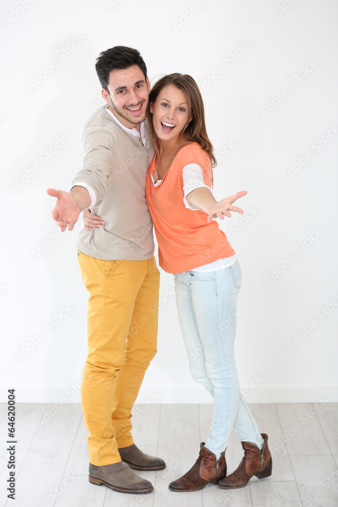 Cheerful couple spreading arms towards camera Cheerful couple spreading arms towards camera