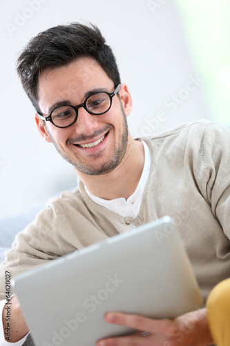 Young man with eyeglasses websurfing with tablet