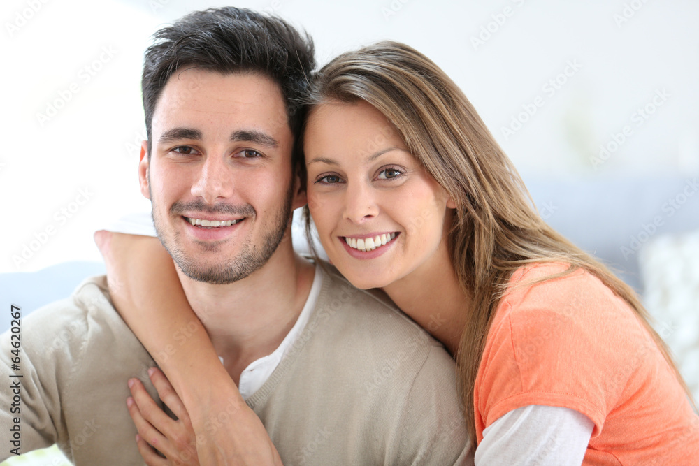 Cheerful couple at home sitting in sofa