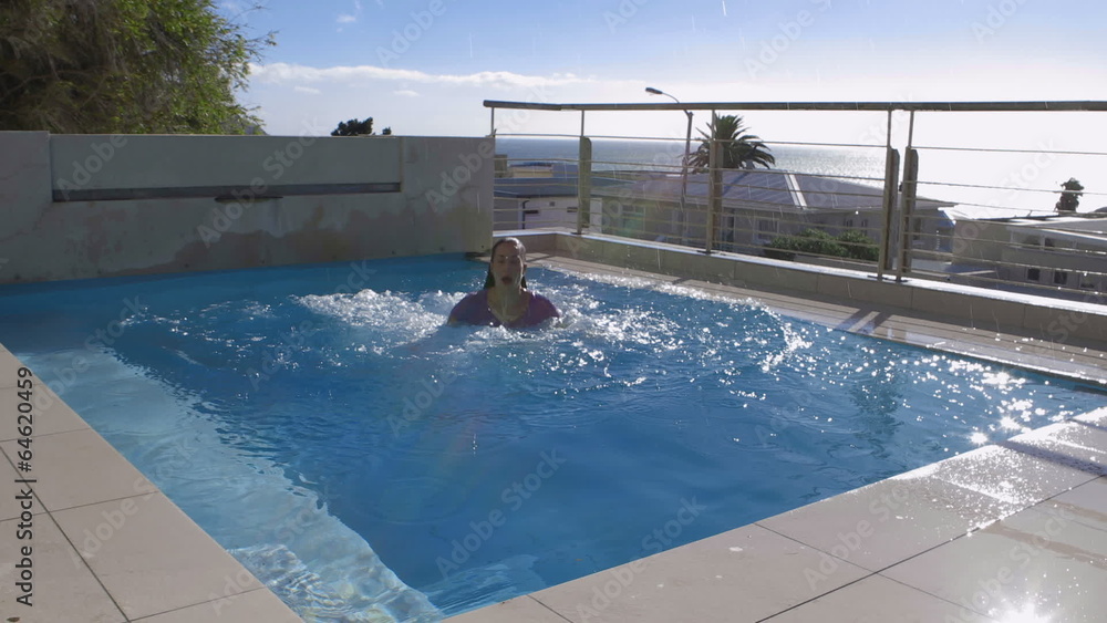 Woman jumping into pool fully clothed