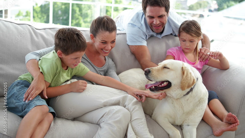 Cute family relaxing together on the couch with their dog Cute family relaxing together on the couch with their dog