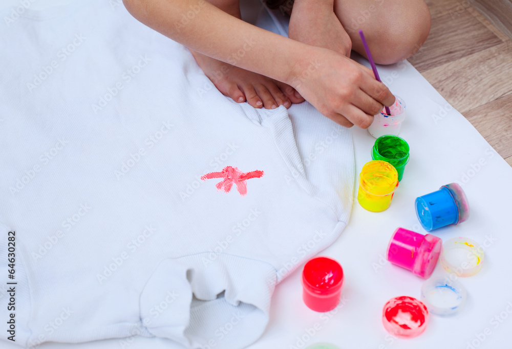 Closeup of child's hands painting white blouse Closeup of child's hands painting white blouse