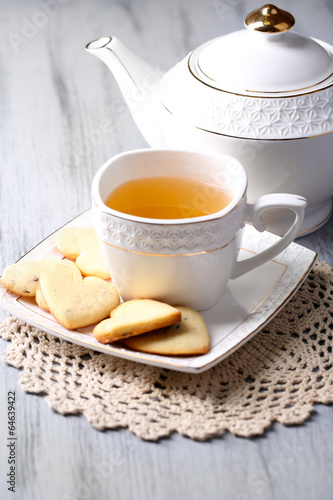Lavender cookies and cup of tasty tea on color wooden