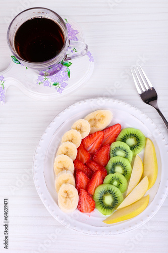 Various sliced fruits on plate on table close-up