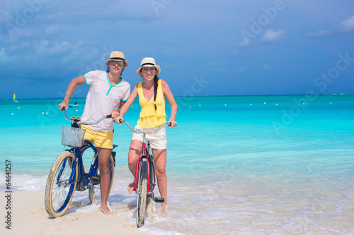 Young happy couple with bikes on white tropical vacation
