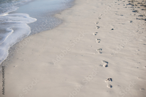 Human footprints on white sand of the Caribbean island