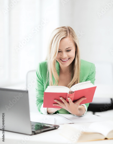 smiling student girl reading book in college