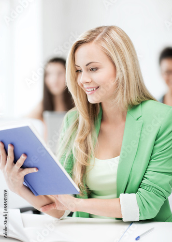 smiling young girl reading book at school