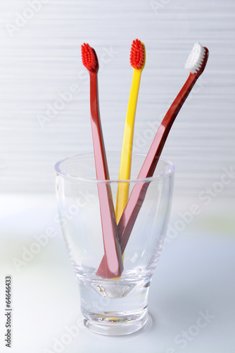 Toothbrushes in glass on table on light background © Africa Studio