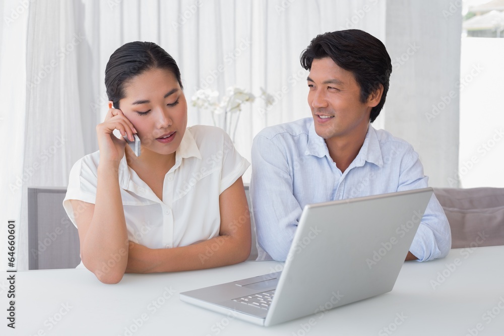 Couple using laptop with woman talking on phone Couple using laptop with woman talking on phone