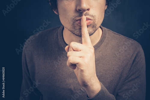Young man with his finger on his lips