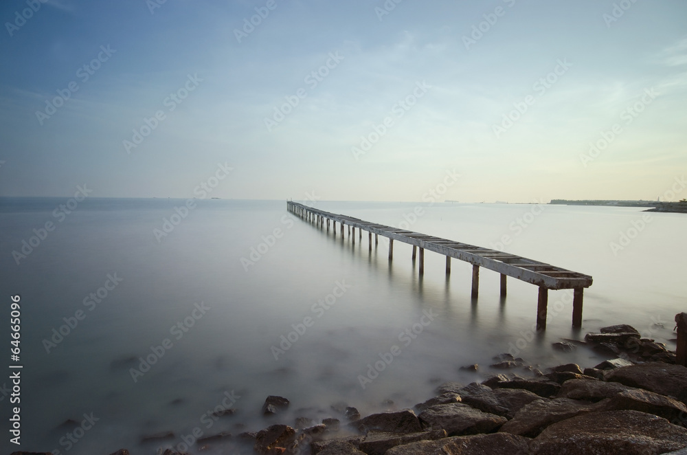 Obraz premium Broken bridge and waves crashing on sea at during sunset