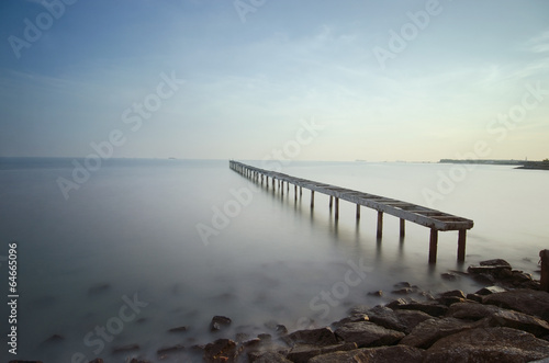 Broken bridge and waves crashing on sea at during sunset