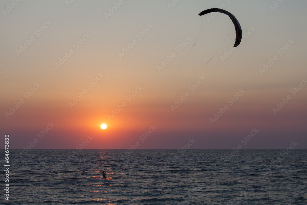 Silhouette of a kitesurfer sailing at sunset Silhouette of a kitesurfer sailing at sunset