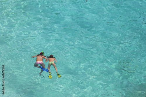 Two girls swimming while wearing snorkeling gear in water