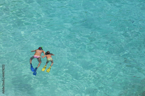 Two girls swimming while wearing snorkeling gear in water