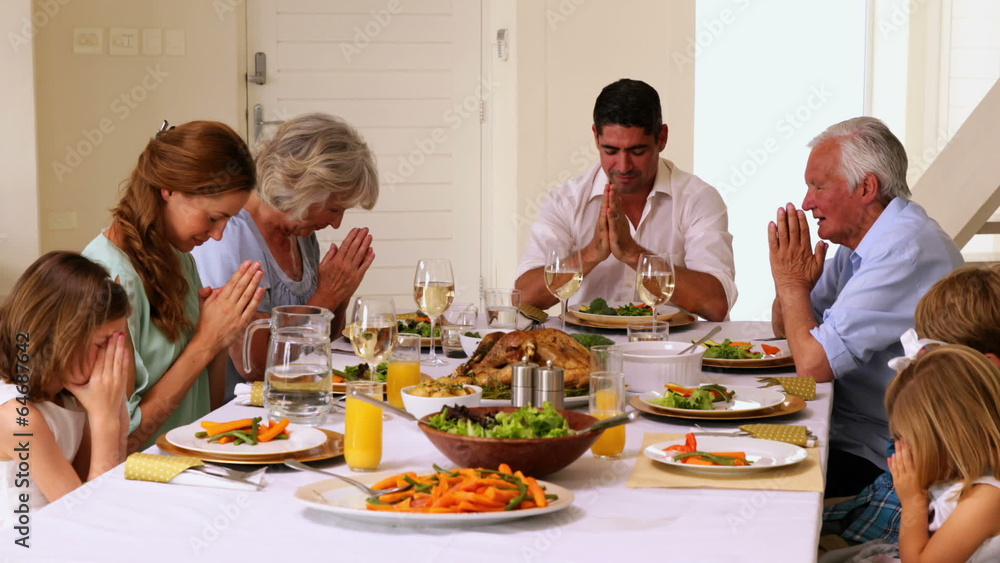 Extended family saying grace together before dinner Extended family saying grace together before dinner