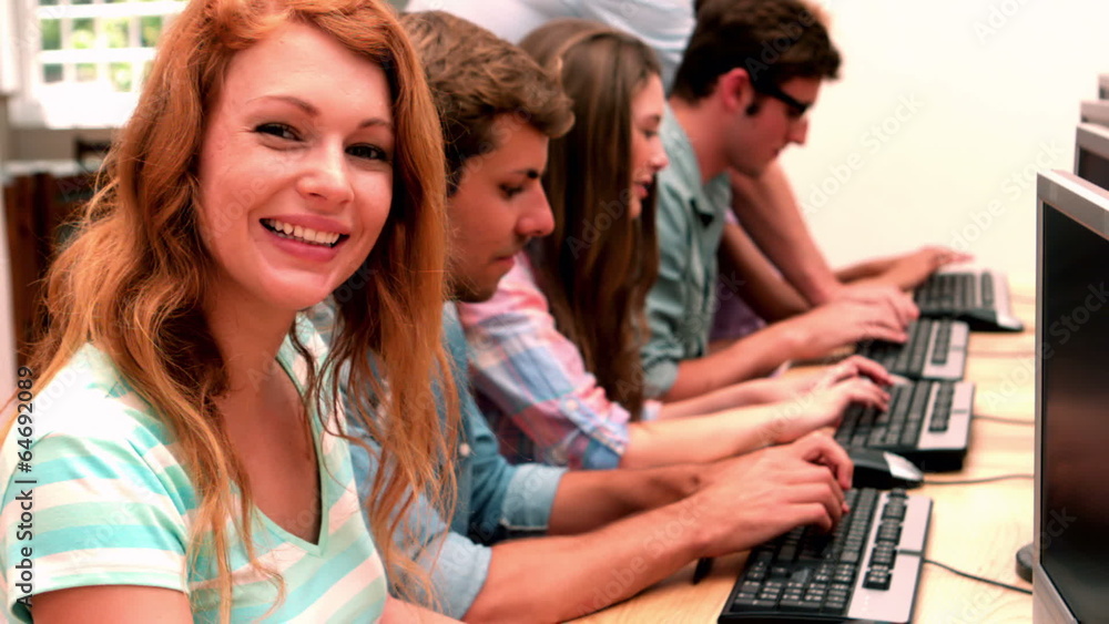 Happy student smiling at camera in computer class Happy student smiling at camera in computer class