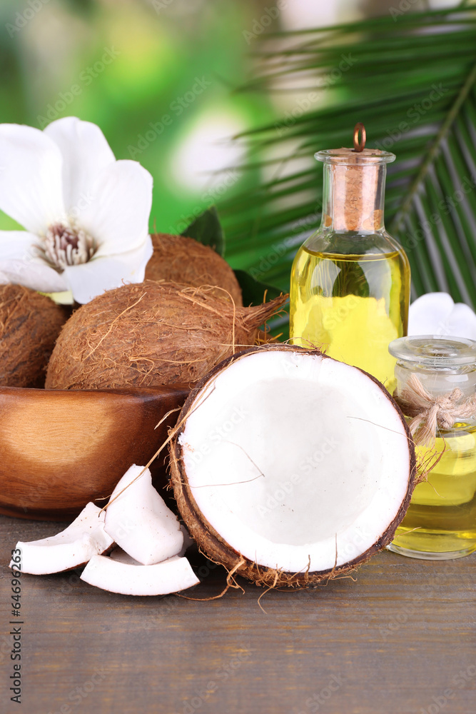 Coconuts and coconut oil on wooden table, on nature background Coconuts and coconut oil on wooden table, on nature background