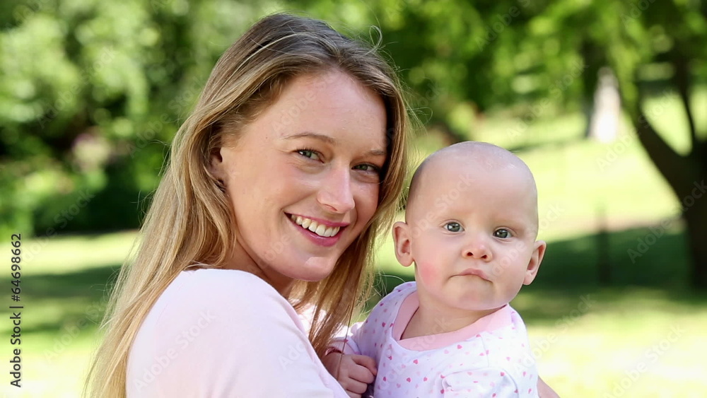 Happy mother holding her baby girl in the park Happy mother holding her baby girl in the park