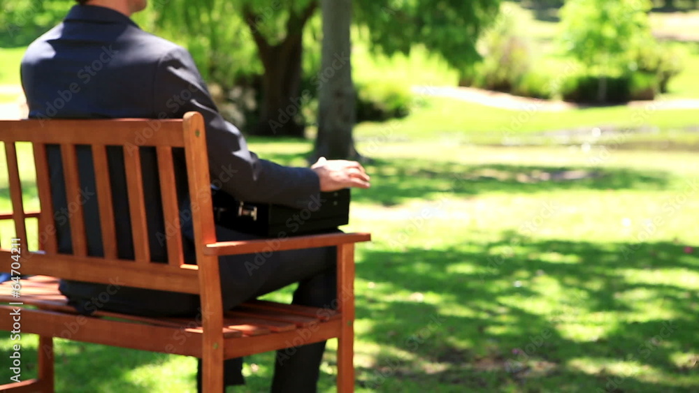 Businessman sitting down on park bench Businessman sitting down on park bench