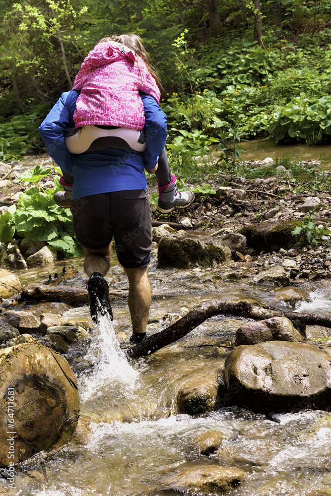 Father who helps his daughter to pass a river Father who helps his daughter to pass a river