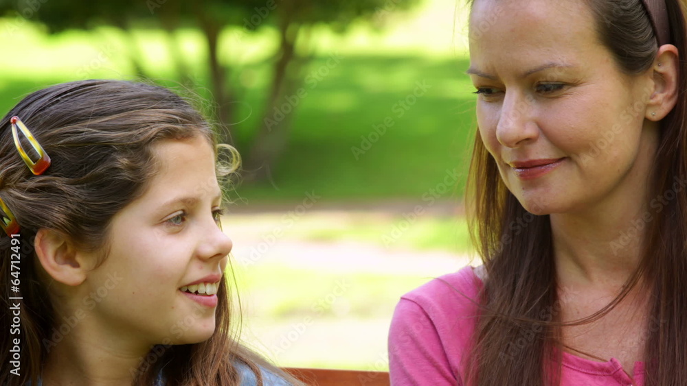 Mother and daughter chatting on a park bench Mother and daughter chatting on a park bench