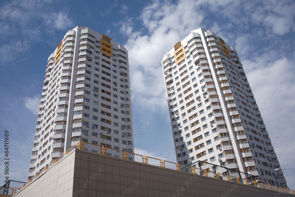 Two residential buildings in a city over blue sky with clouds Two residential buildings in a city over blue sky with clouds