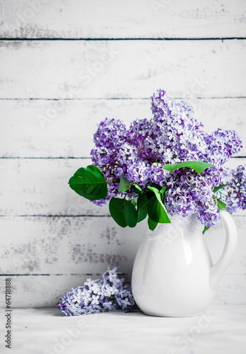 Lilacs in white vase on rustic background