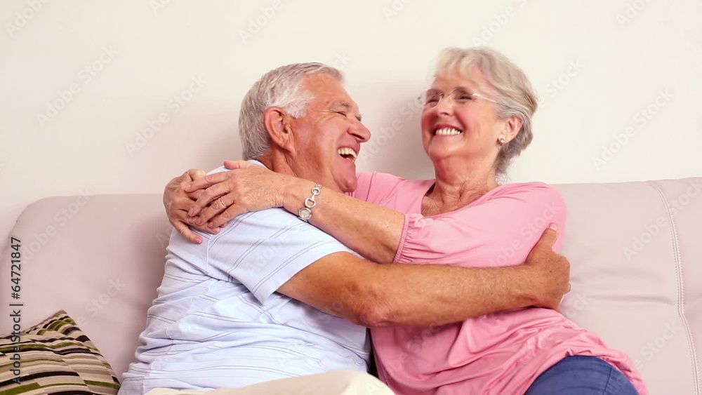 Senior couple sitting on sofa hugging Senior couple sitting on sofa hugging