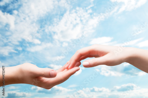 Man and woman hands touch in gentle, soft way on blue sunny sky © Photocreo Bednarek