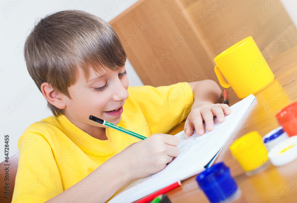 Beautiful boy sitting at a table painting and smiling Beautiful boy sitting at a table painting and smiling