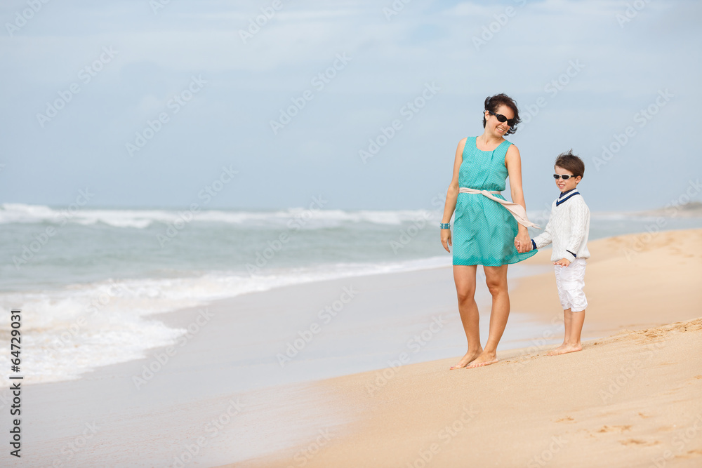 Mother and son walking along a tropical beach Mother and son walking along a tropical beach