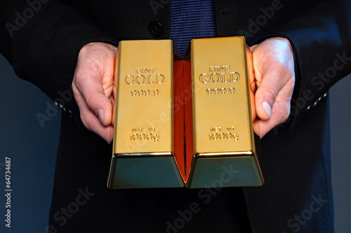 Businessman holds at hands gold brick