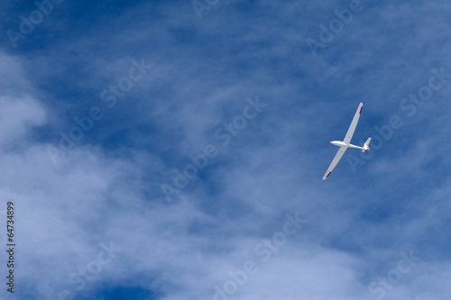 A glider flying across the blue sky