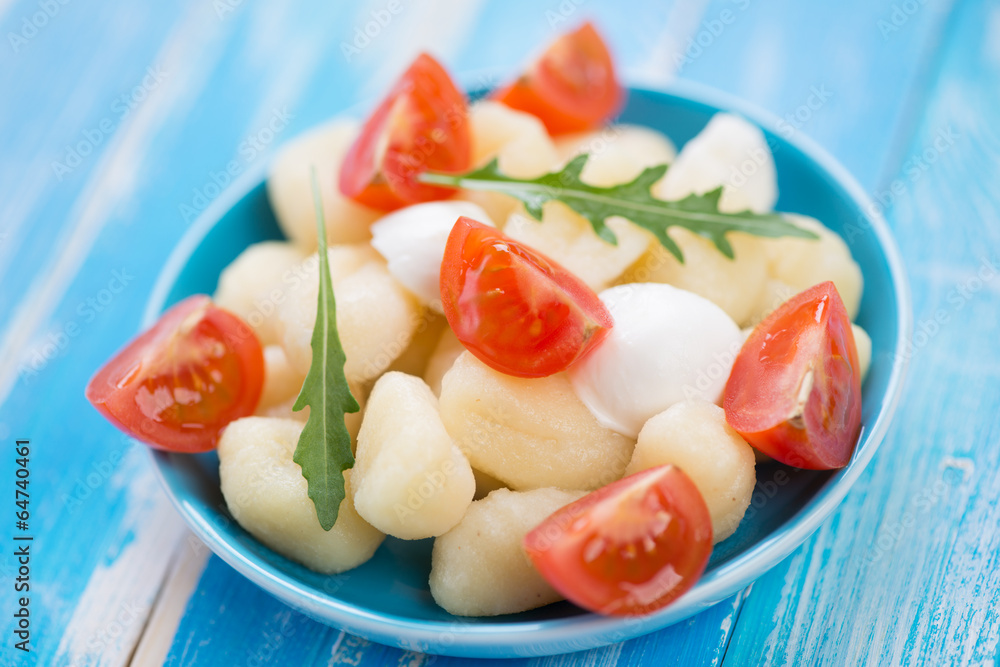 Boiled italian gnocchi with sliced cheese, tomatoes and arugula