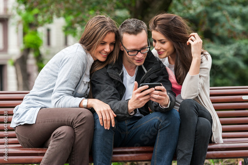 Three friends looking at an image on a smartphone