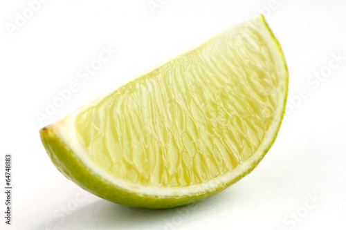 Lime wedges arranged on a white surface. Selective focus.